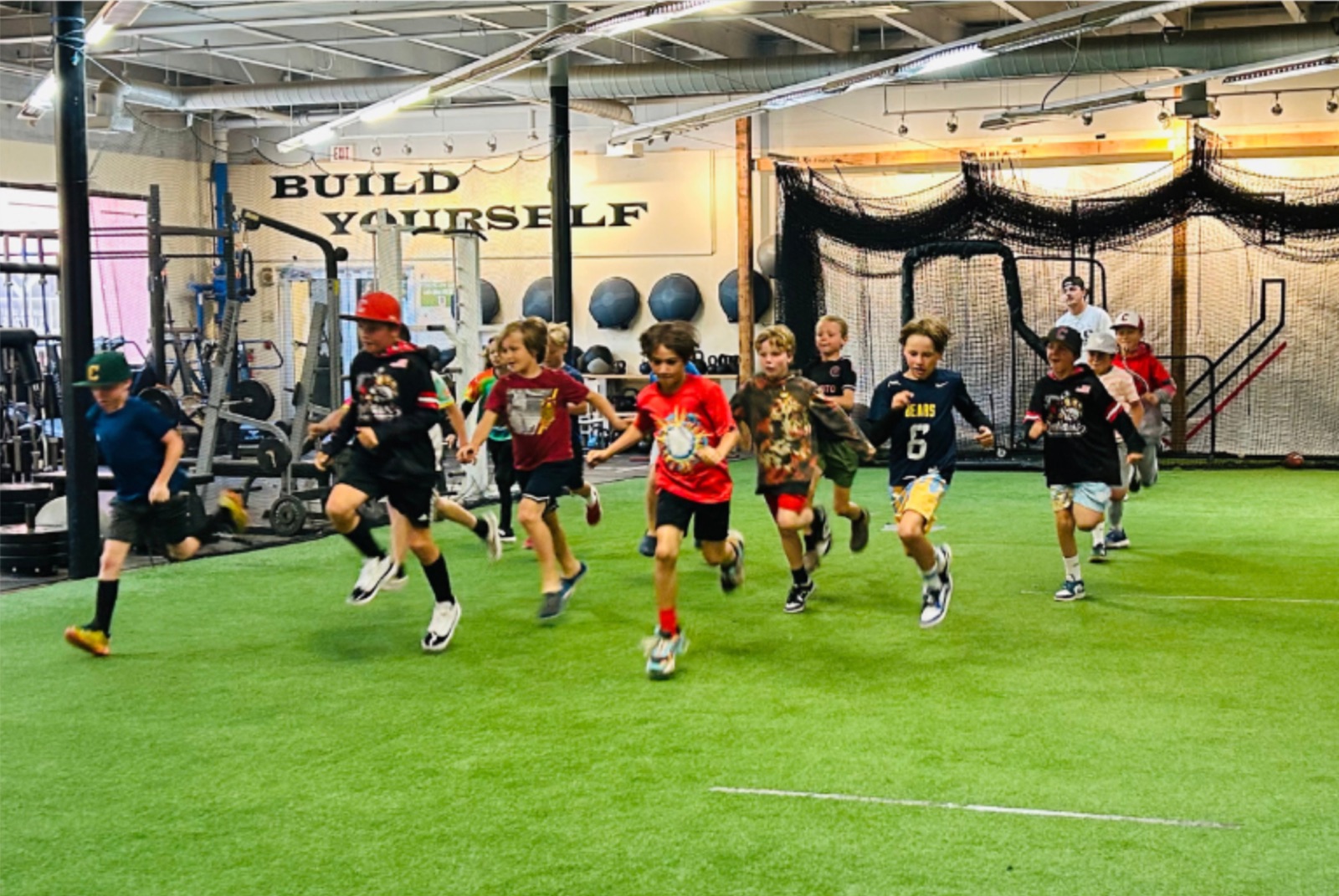 A group of young baseball players running sprints on the turf at The Clubhouse
