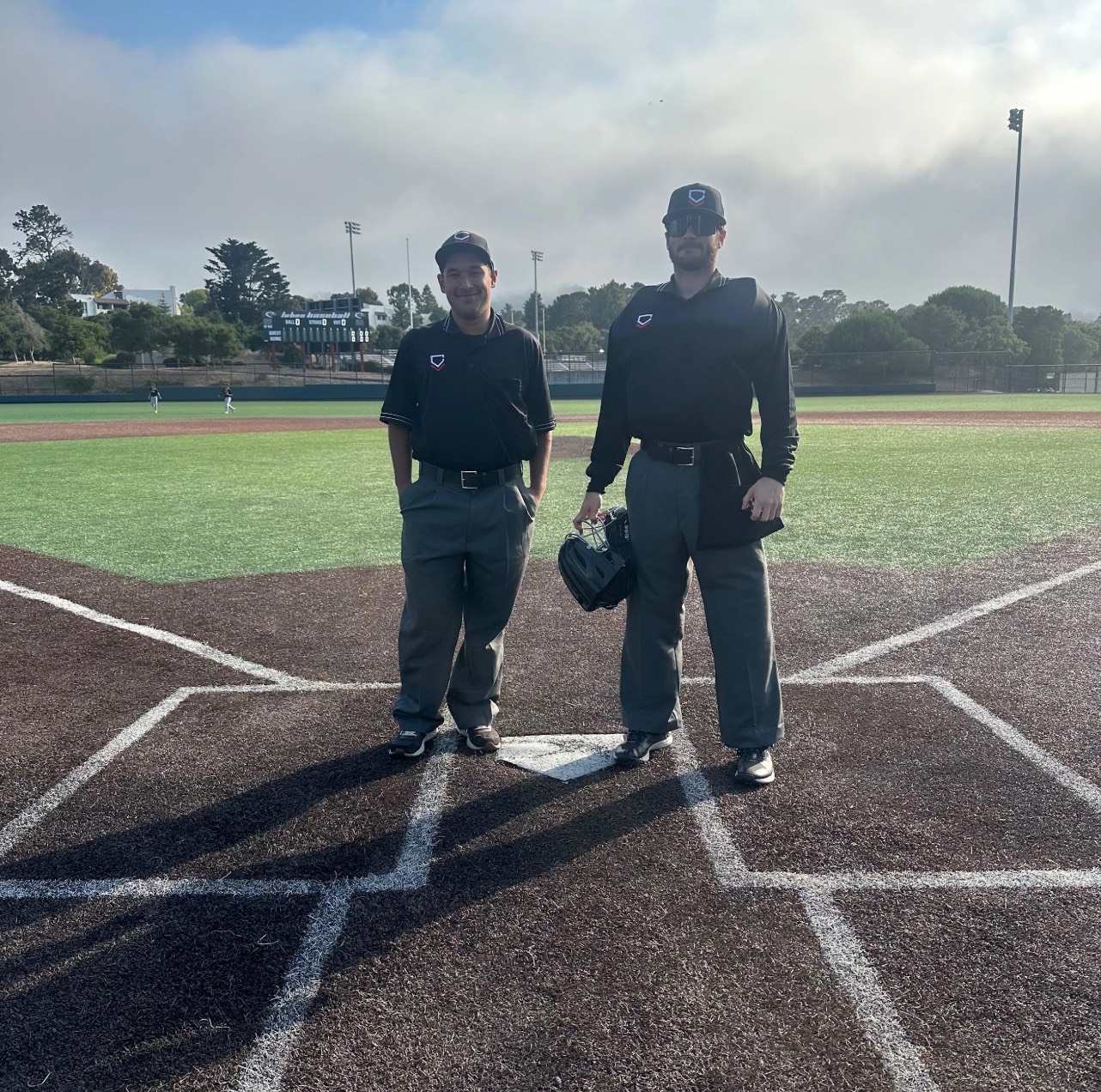 Two umpires in uniform standing at home plate before a game